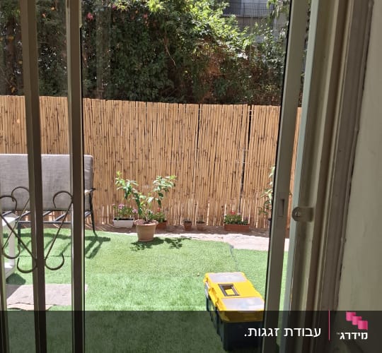 דלת הזזה מזכוכית המובילה לחצר עם דשא סינתטי
